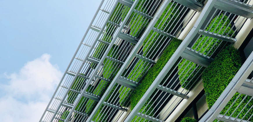 A vertical garden covering the side of a multi-story building, with lush green plants growing in between the metal framework.