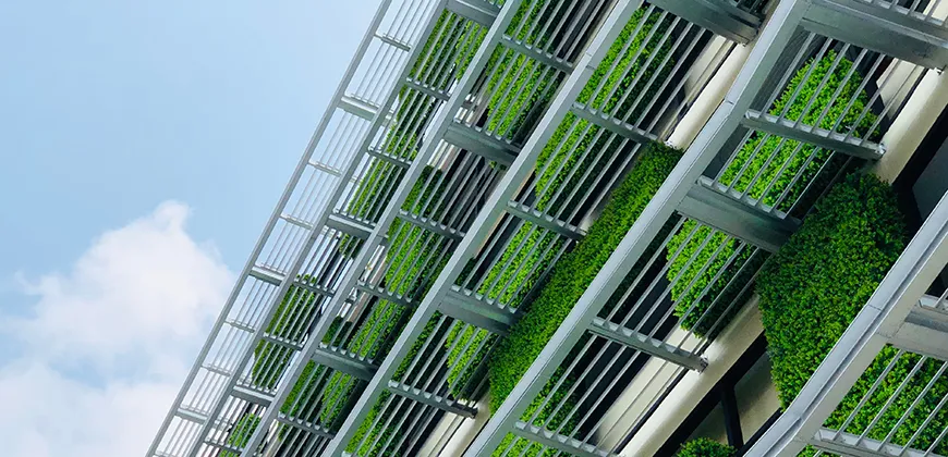 A vertical garden covering the side of a multi-story building, with lush green plants growing in between the metal framework.