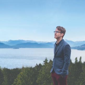 Engineer standing by forested mountains and the ocean